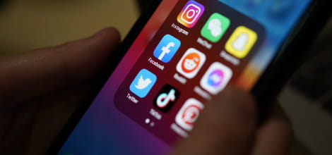Close up image of iphone with showing a folder containing social media icons